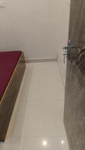 a bathroom with a white tile floor and a shower at Kashi kedar paying guest house in Varanasi