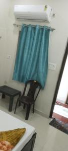 a chair in a room with a blue curtain at Kashi kedar paying guest house in Varanasi