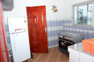 a kitchen with a white refrigerator and a red door at Résidence DON BOSCO in Douala
