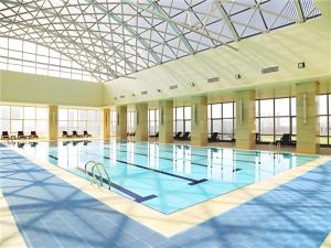 a large indoor swimming pool with a glass ceiling at Jiuhua Jin Jiang International Hotel in Zhenjiang