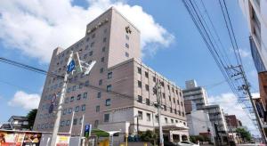 a tall white building on a city street at Albert Hotel in Akita