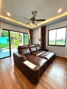 バーン・クロンムアンにあるSmile Home Krabi Klong Moung Beachの窓付きのリビングルーム(ブラウンレザーのソファ付)