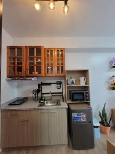 Una cocina con armarios de madera, fregadero y microondas. en Dylan's Crib, en Bacolod 2 fotos más