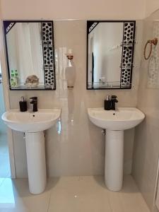 Dos lavabos en un baño con dos espejos en Ivory Room Lableva Court, en Lusaka