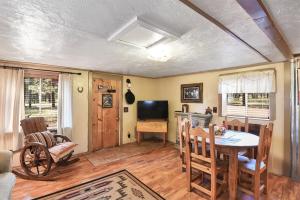 Una sala de estar con una mesa y un televisor. en Rustic Adventure w Historic Log Cabin Forest Views 20 minutes from Flagstaff Now with Wi-Fi, en Parks