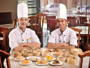 two chefs sitting at a table with food at Sea Lion Hotel @ Klang in Klang
