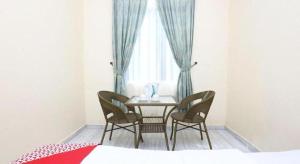 a table and chairs in a room with a window at OYO 89607 Aloha Chalet in Kampung Raja