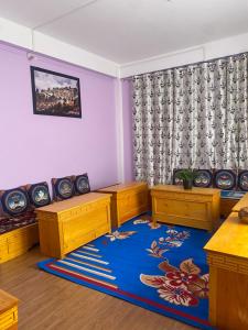 a living room with wooden furniture and a blue rug at Norkyi Homestay in Tawang