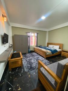 a bedroom with two beds and a tv in it at Norkyi Homestay in Tawang