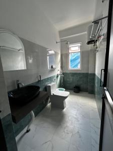 een badkamer met een zwarte wastafel en een toilet bij Norkyi Homestay in Tawang