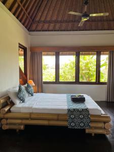 a bedroom with a large bed in a room with windows at In Da Lodge in Ubud