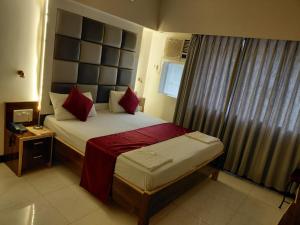 a bedroom with a large bed with red pillows at Hotel Woodland in Mumbai