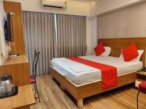 a bedroom with a bed with red pillows and a television at Hotel Woodland in Mumbai