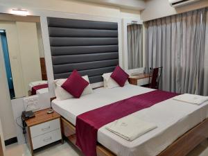 a bedroom with a large bed with purple pillows at Hotel Woodland in Mumbai