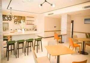 a restaurant with tables and chairs and a kitchen at City Comfort lnn Dayi High-speed Railway Station in Chengdu