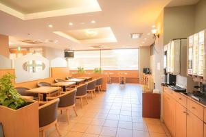 a restaurant with tables and chairs in a cafeteria at Smile Hotel Nishiakashi in Kobe