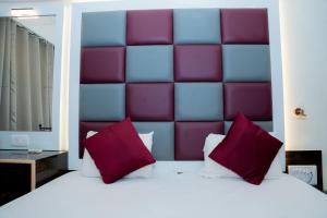 a bedroom with a large bed with red and purple pillows at Hotel Woodland in Mumbai