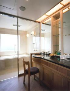 a bathroom with a sink and a chair and a mirror at Grand Hotel New Oji in Tomakomai