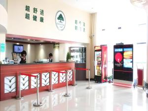 un ristorante con un bancone e due persone in un edificio di GreenTree Inn Shanghai Jiading Anting Motor City Express Hotel a Shanghai