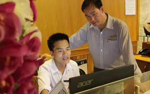 Thu Dau MotにあるAu Lac Hotelのコンピューターの前に立っている二人の男性