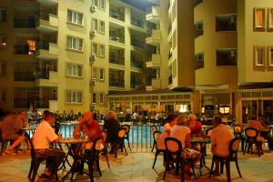 a group of people sitting at tables in front of a building at Kleopatra Royal Palm Hotel in Alanya