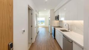 cocina con encimeras blancas y suelo de madera en Aero Apartment, en Alameda