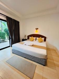 a bedroom with a large white bed with yellow pillows at Lanta Nesta Resort in Ko Lanta Yai