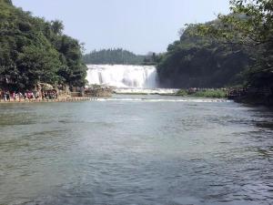 a view of a river with a waterfall in the background at IU Hotel Anshun Zhenning Huangguoshu Scenic Area Toursit Center in Anshun