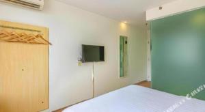Un dormitorio con una cama y un televisor en una pared. en 7 Days Inn West Gate of Taiyuan University of Technology, en Taiyuán