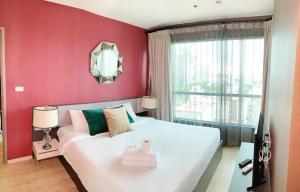a bedroom with a large white bed with a red wall at THE BASE Central Pattaya Sea View Holiday Residences in Pattaya Central