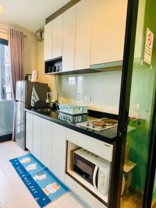 a kitchen with white cabinets and a microwave at The base Central 1006 by Numam in Pattaya