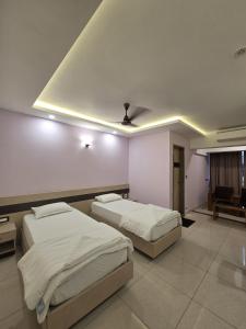 a bedroom with two beds and a ceiling at Krishnavasyam lodging in Uppinangadi
