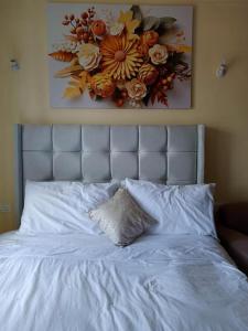 a white bed with a flower picture on the wall at Elegant homes , KENYA in Nairobi