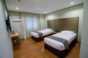 Habitación de hotel con 2 camas y TV en Madison Hotel PHL, en Iloilo City