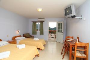 a room with two beds and a table and a television at Premedinos inn in Lazaráta