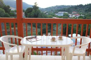Premedinos inn في Lazaráta: طاولة بيضاء وكراسي على شرفة مطلة