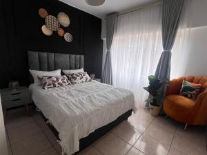 een slaapkamer met een bed en een stoel bij Bright and airy Harare CBD flat in Harare