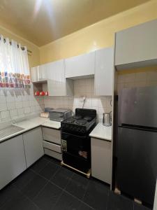 een keuken met witte kasten en een zwarte kachel bij Bright and airy Harare CBD flat in Harare