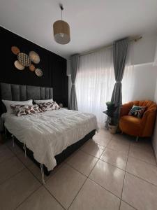 een slaapkamer met een bed en een stoel bij Bright and airy Harare CBD flat in Harare +17 foto's