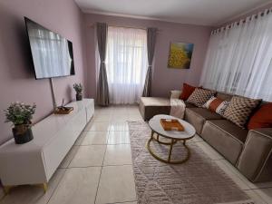 een woonkamer met een bank en een tafel bij Bright and airy Harare CBD flat in Harare