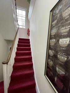 a staircase with red carpet and a painting on the wall at Oban Victoria Hotel in London +23 photos