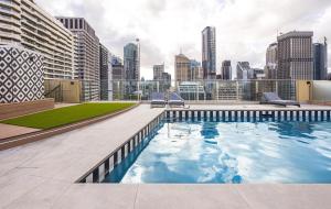 a swimming pool on top of a building with a city skyline at Accommodation Sydney - Hyde Park Plaza 38 College St Sydney in Sydney