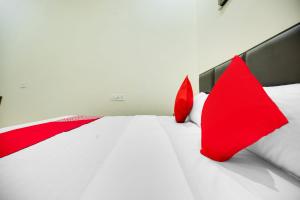 a bedroom with red pillows on a white bed at Hotel O Sky Line in Ludhiana