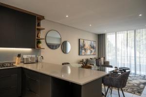 a kitchen with a large white counter and chairs at Lux Leisure Apartment Hotel Sandton in Johannesburg