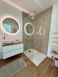 a bathroom with a shower with a sink and a mirror at Maison Familiale plain pied à 2km de la mer in Trignac