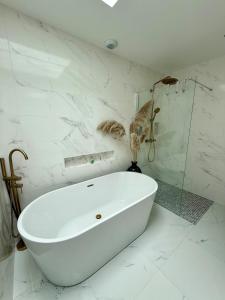 a white bath tub in a bathroom with marble walls at Maison Familiale plain pied à 2km de la mer in Trignac