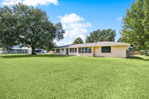 a house with a large grass field in front of it at Cozy home close to it ALL in Gonzales