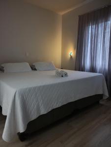 a bedroom with a bed with white sheets and a window at casa para Oktoberfest in Blumenau +10 photos
