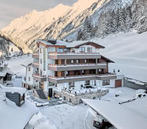 een gebouw in de sneeuw met bergen op de achtergrond bij Hotel Garni Schönblick in Sölden