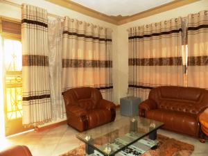 sala de estar con 2 sillas de cuero y mesa en Capricon Executive Hotel Kabale en Kabale